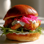 Bronzed Fish Sandwich with Homemade Tartar Sauce and Pickled Onions on a Toasted Brioche Bun